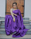 Model wearing a purple checked saree with a subtle zari grid and matching drape, paired with a printed blouse.